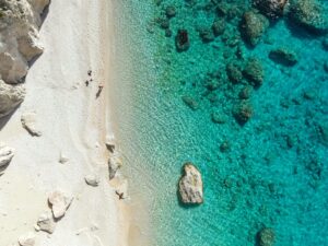 Stunning aerial view of a secluded beach with turquoise waters and rocky shoreline.
